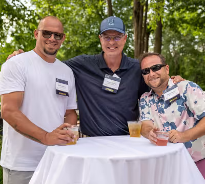 three people standing around cocktail table smiling