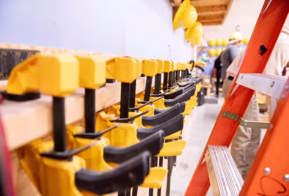 A row of wood clamps in storage on the side of a wall.