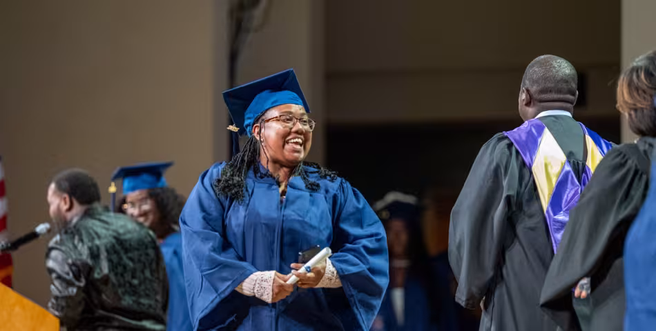 Summit graduate walking across stage in cap and gown at commencement