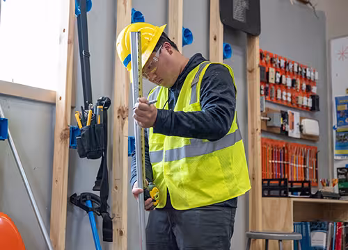 Electrician student measuring pipe