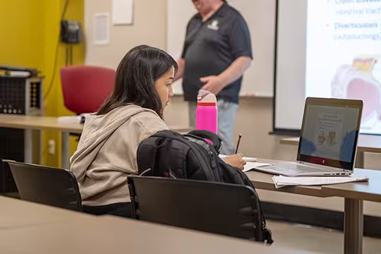Medical Administrative Assistant student taking notes in classroom