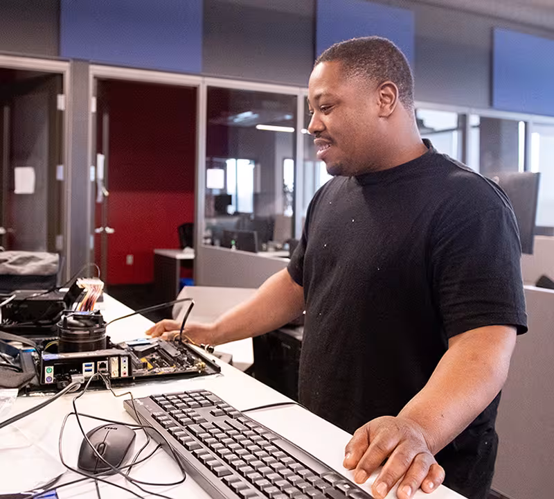 IT student in classroom learning hands on with computer hardware