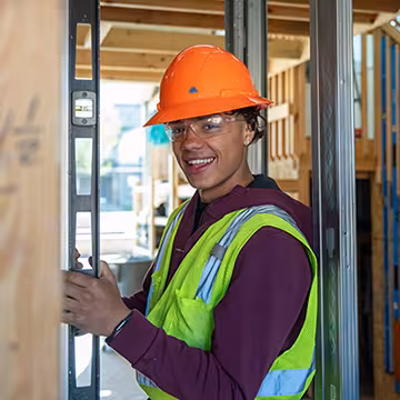 Carpentry student at Summit using a level and smiling at the camera