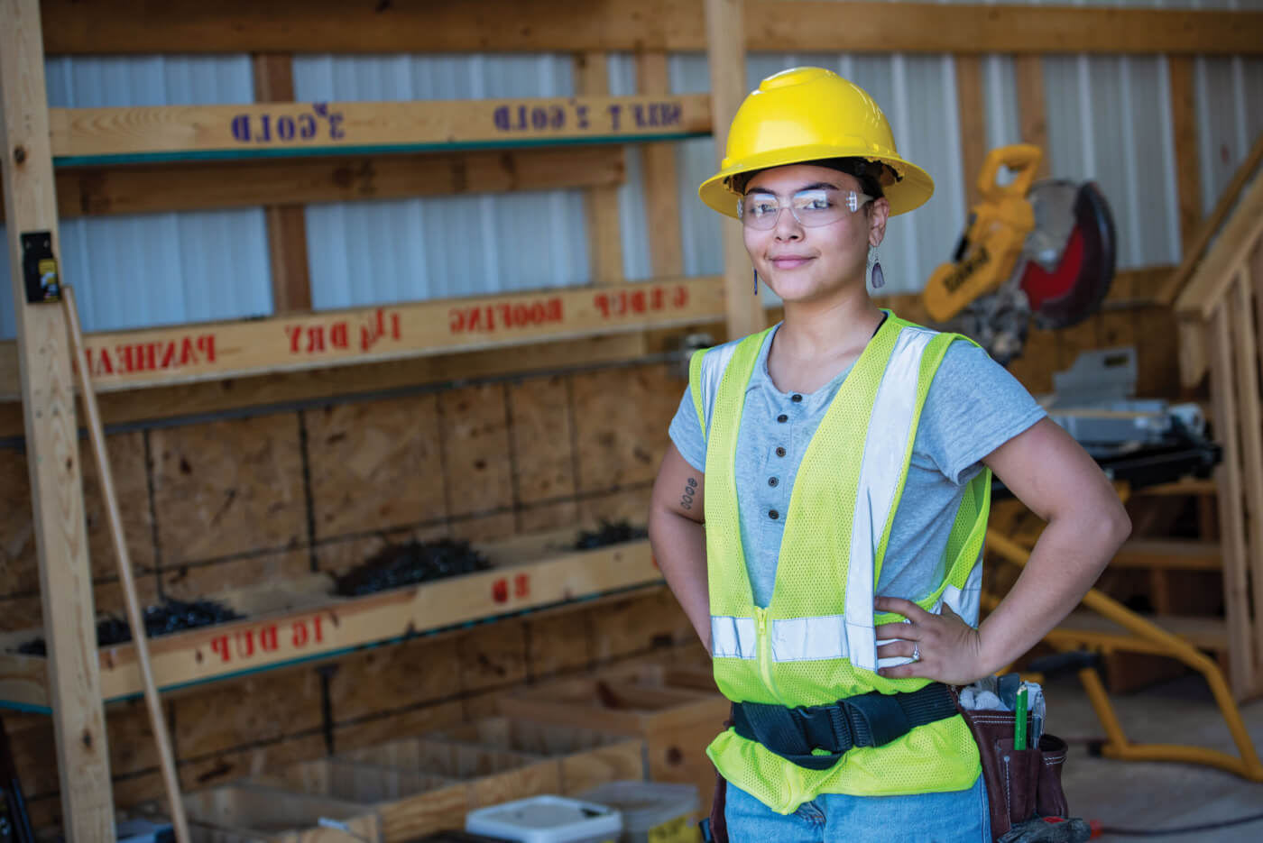 Female Construction student in hard hat and green vest.